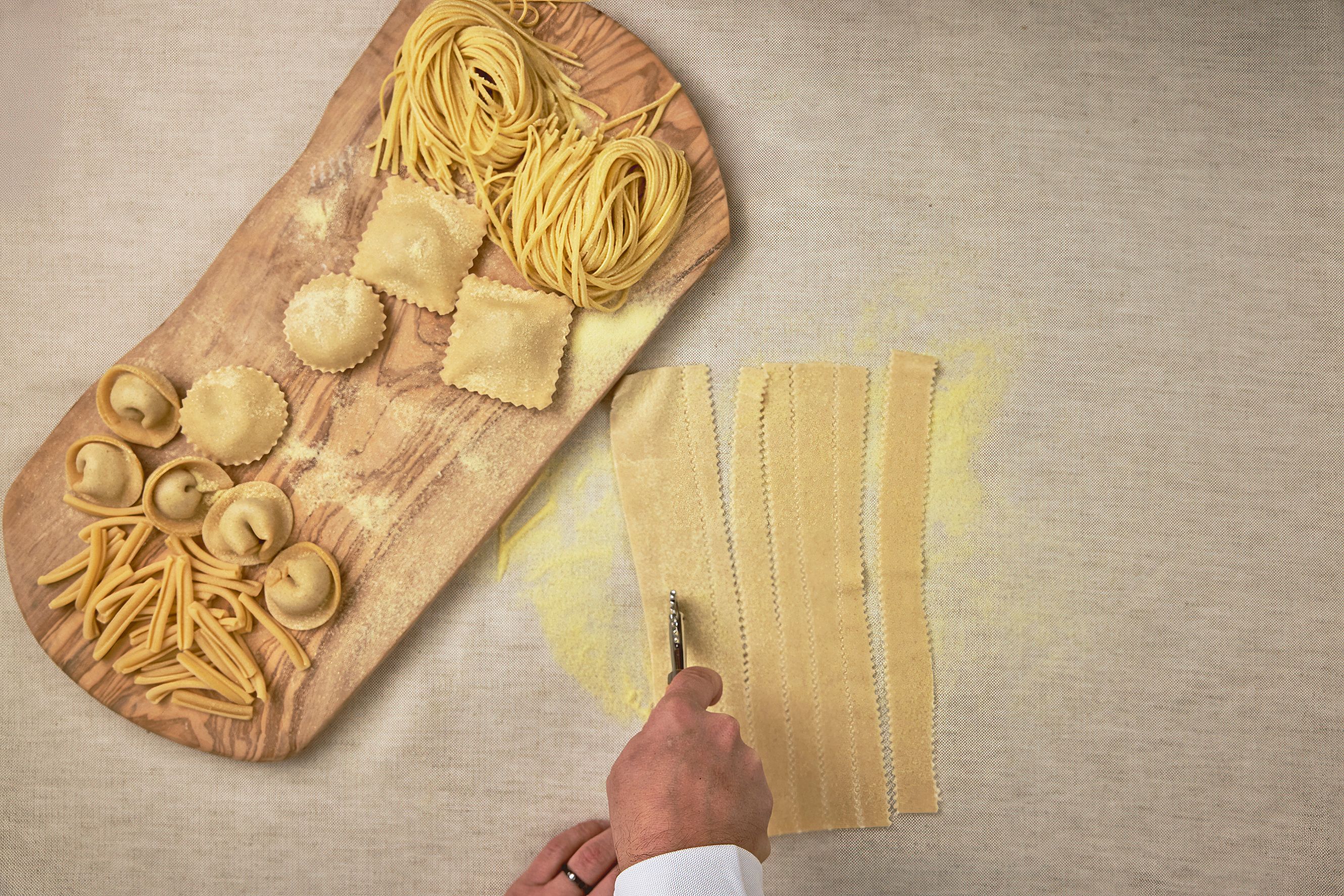 Seia Miami Chef Cutting Uncooked Pasta With A Wooden Board Of Pasta Types